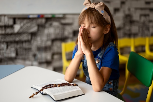 Chica de vista lateral rezando en la escuela dominical
