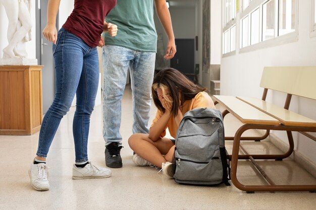 Chica de vista lateral siendo acosada en la escuela