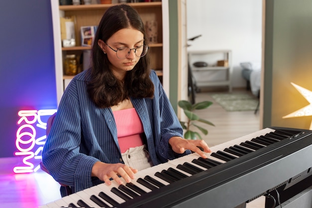 Foto gratuita chica de vista lateral tocando el piano en casa