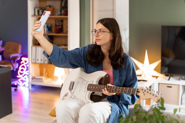 Chica de vista lateral tomando selfie en casa