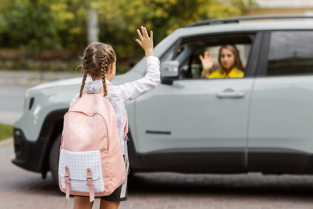 Chica de vista trasera saludando a la madre