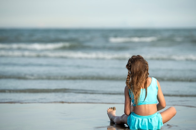 Chica de vista trasera sentada en la playa