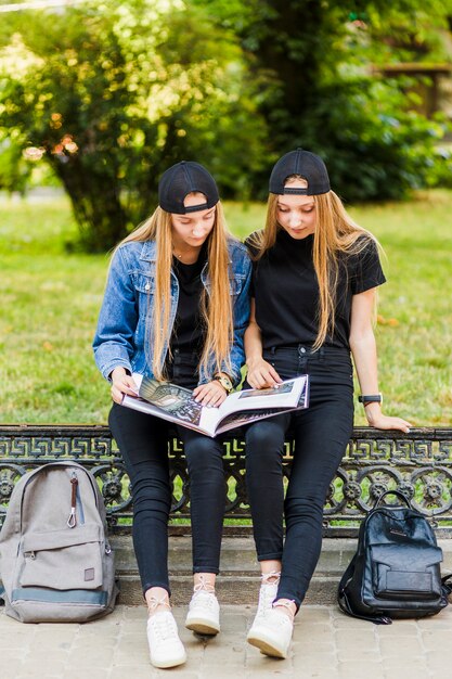 Chicas adolescentes leyendo el libro en la cerca