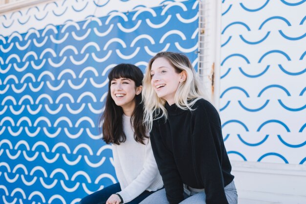 Chicas alegres que ríen mientras observan la calle