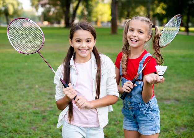 Chicas alegres con raquetas de bádminton en la mano