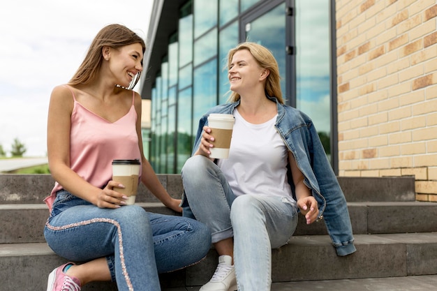 Chicas de ángulo bajo charlando y bebiendo su café