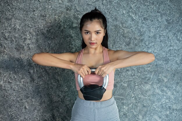 Las chicas asiáticas hacen ejercicio con el Kettlebell en el gimnasio.