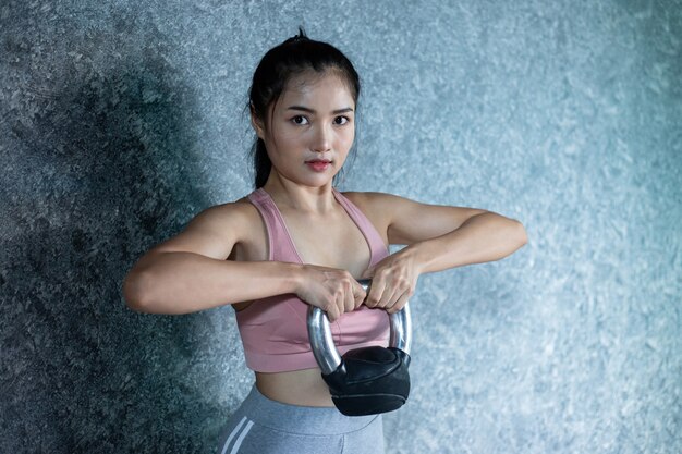 Las chicas asiáticas hacen ejercicio con el Kettlebell en el gimnasio.