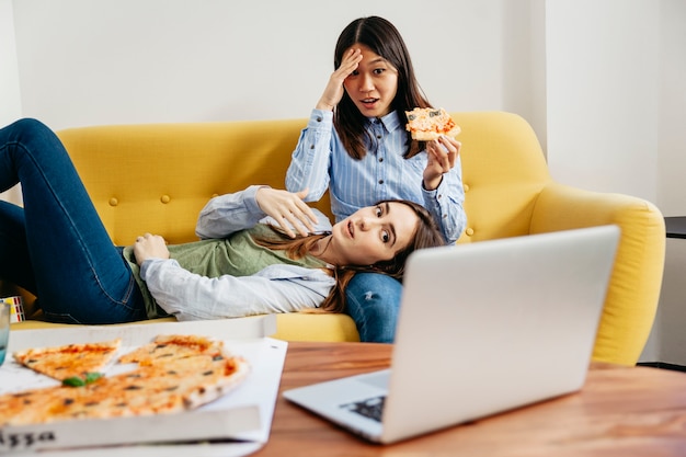 Chicas asustadas viendo películas con pizza