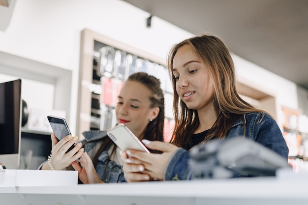 Chicas atractivas jóvenes en tienda de electrónica comprar teléfono nuevo