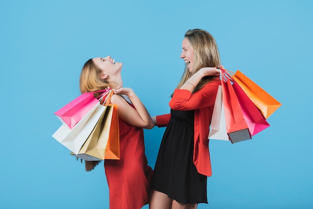 Chicas con bolsas de compras en fondo liso