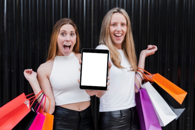 Chicas con bolsas de compras con maqueta de tableta