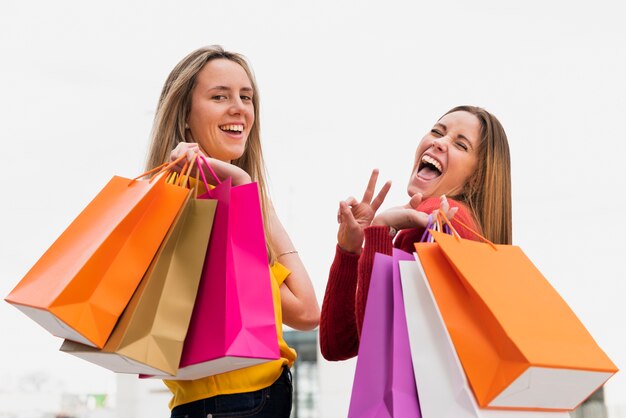 Chicas con bolsas de compras mirando a la cámara