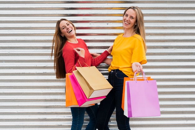 Chicas con bolsas de compras mirando a la cámara