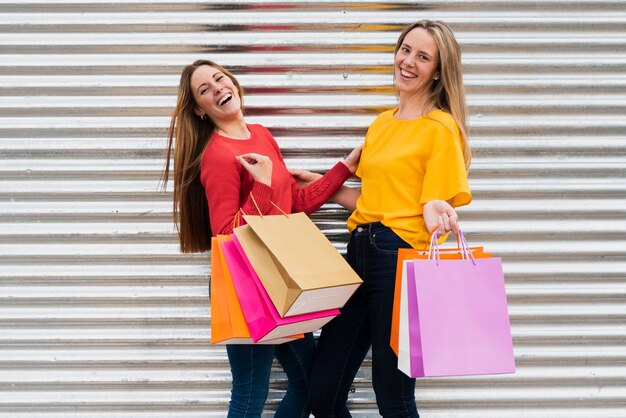 Chicas con bolsas de compras mirando a la cámara