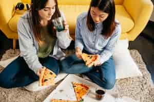 Foto gratuita chicas bonitas con pizza en el piso