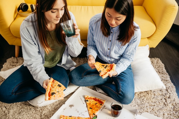 Chicas bonitas con pizza en el piso