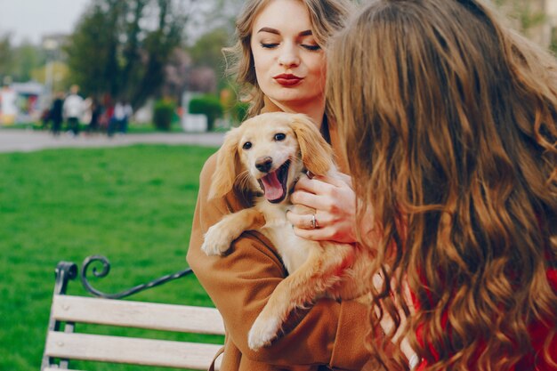 Las chicas caminan en el parque con perro.