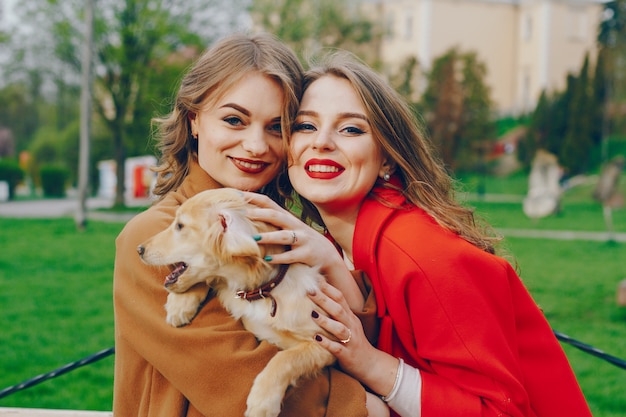 Las chicas caminan en el parque con perro.