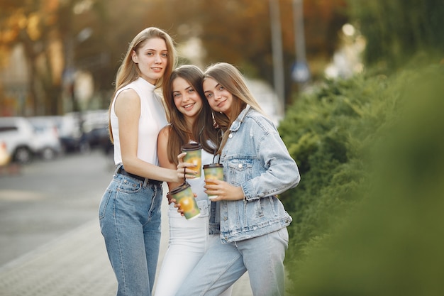 Chicas caminando en una ciudad de primavera y tomando café