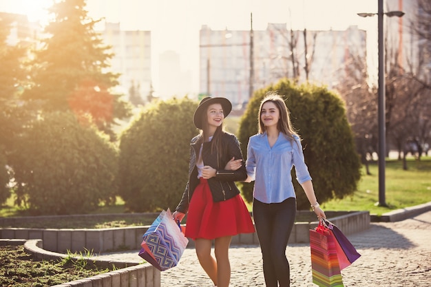 chicas caminando con compras en calles de la ciudad