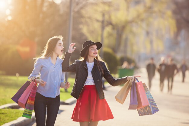 chicas caminando con compras en calles de la ciudad