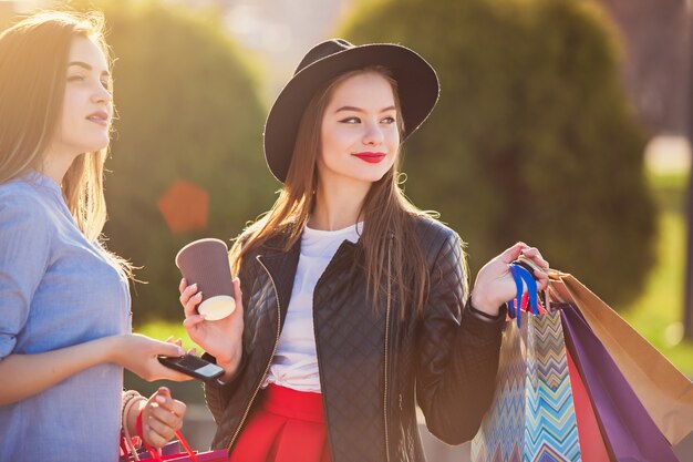 chicas caminando con compras en calles de la ciudad