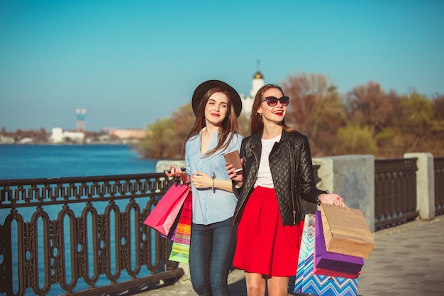 chicas caminando con compras en calles de la ciudad