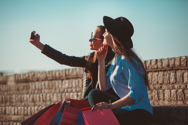 chicas caminando con compras en calles de la ciudad