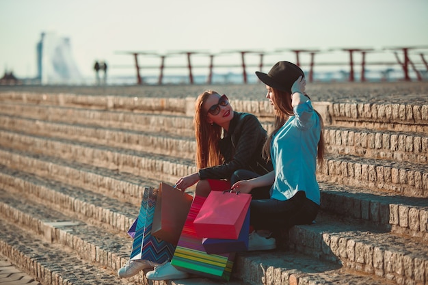 chicas caminando con compras en calles de la ciudad