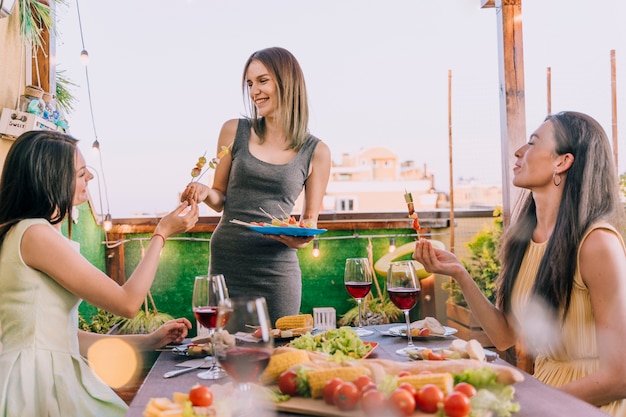 Chicas comiendo aperitivos en la fiesta en la azotea