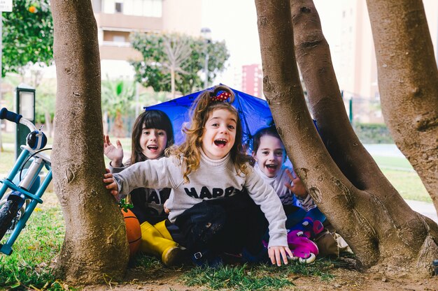 Chicas divertidas sentadas debajo de un árbol