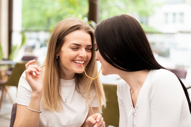 Chicas divirtiéndose con un fideo de espagueti.