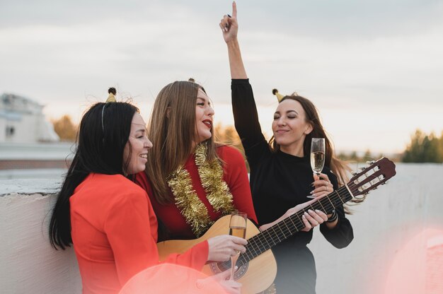 Chicas divirtiéndose con una guitarra en la fiesta de la azotea
