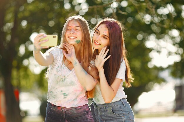 chicas divirtiéndose en un parque con pinturas holi