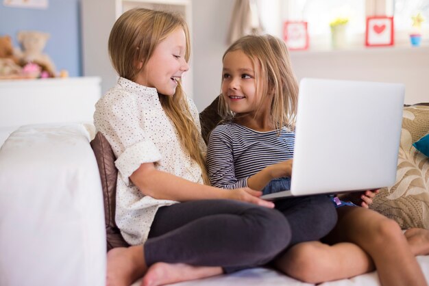 Chicas divirtiéndose con el uso de la computadora portátil