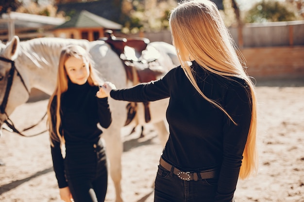 Chicas elegantes con un caballo en un rancho.