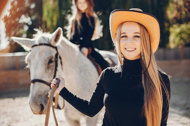 Chicas elegantes con un caballo en un rancho.