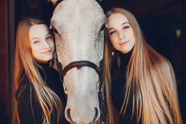 Chicas elegantes con un caballo en un rancho.