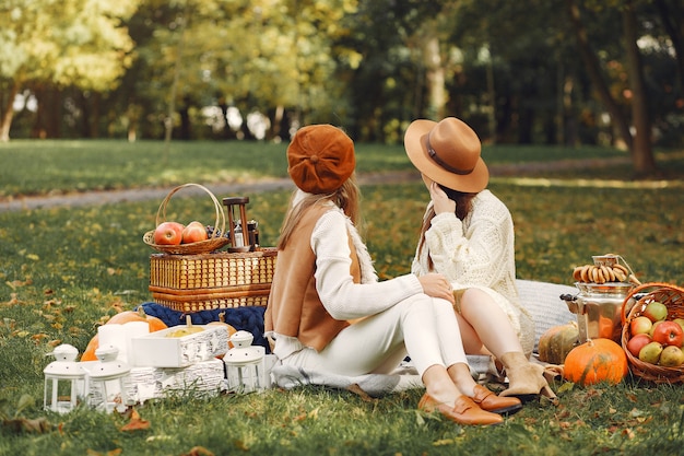Chicas elegantes y con estilo sentadas en un parque