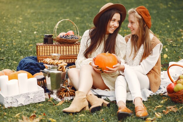 Chicas elegantes y con estilo sentado en un parque de otoño