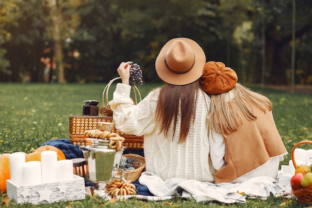 Foto gratuita chicas elegantes y con estilo sentado en un parque de otoño