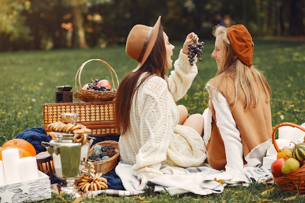 Chicas elegantes y con estilo sentado en un parque de otoño