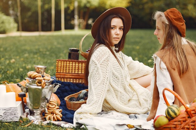 Chicas elegantes y con estilo sentado en un parque de otoño