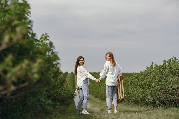 Chicas elegantes y hermosas pintando en un campo