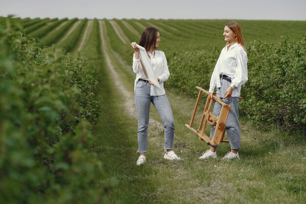 Foto gratuita chicas elegantes y hermosas pintando en un campo