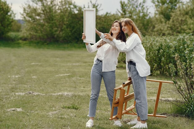 Chicas elegantes y hermosas pintando en un campo