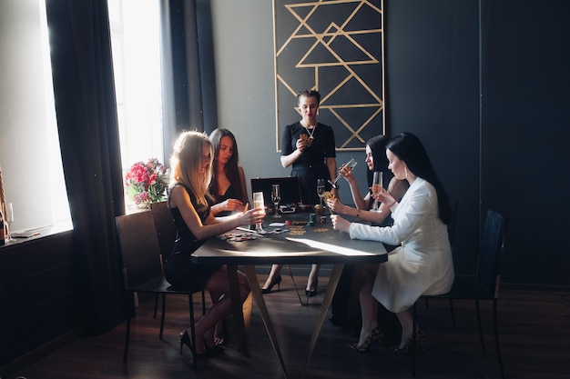 Chicas elegantes en naipes negros y bebiendo champaña