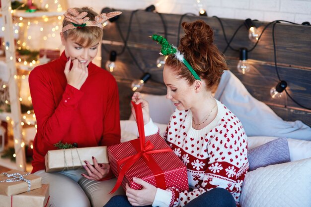 Chicas emocionadas abriendo regalo de Navidad en la cama