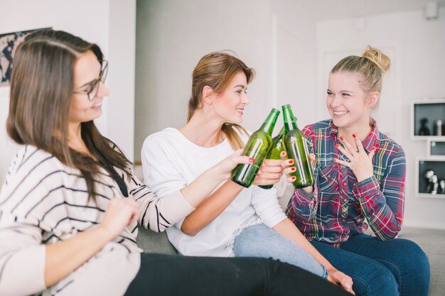 Chicas emocionadas animando con cerveza en casa